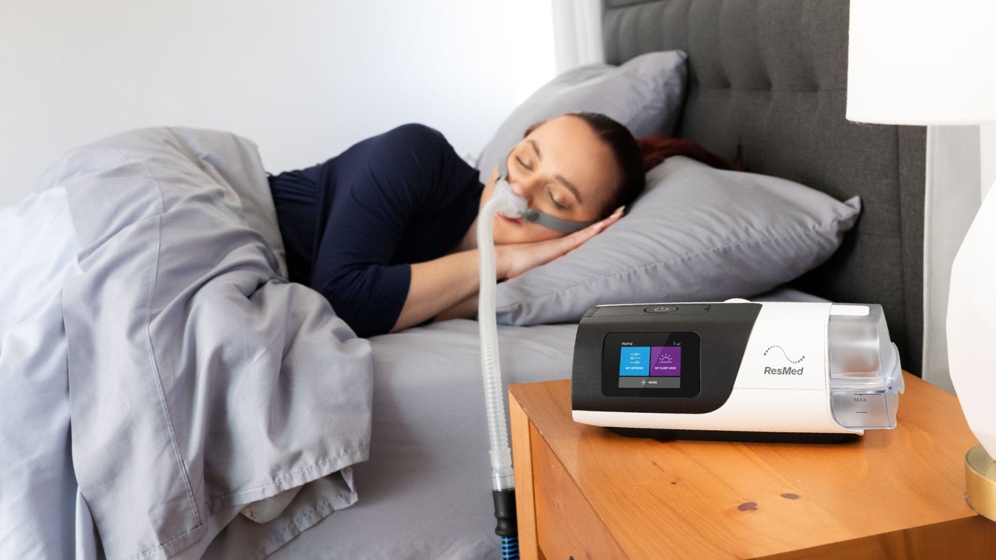 Woman sleeping with a ResMed AirSense on the nightstand