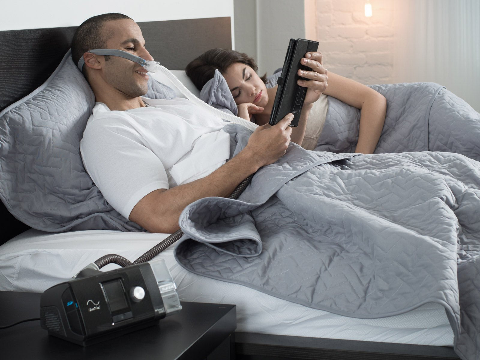 CPAP user relaxing in bed with their partner