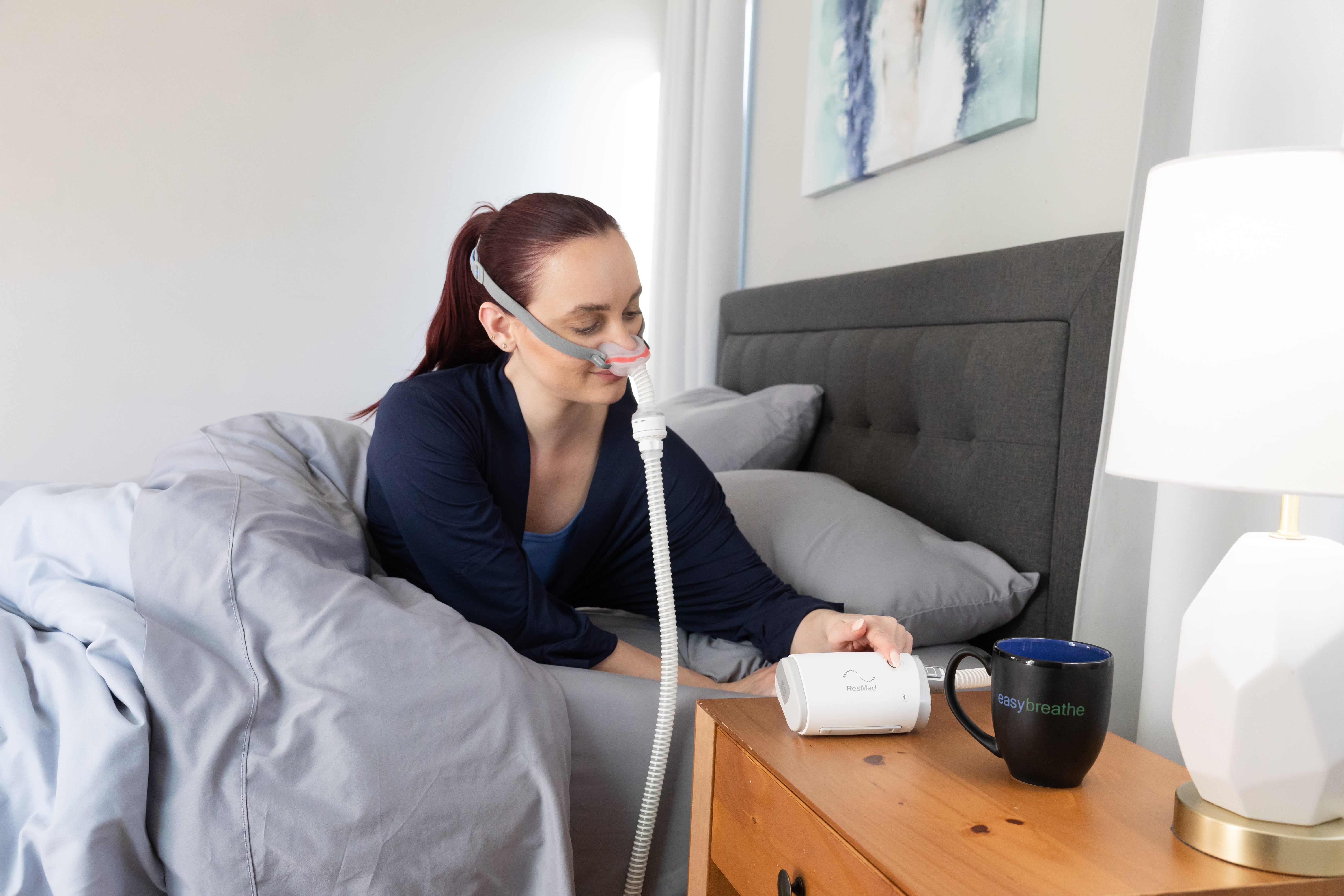 Woman using the ResMed AirMini at her bedside